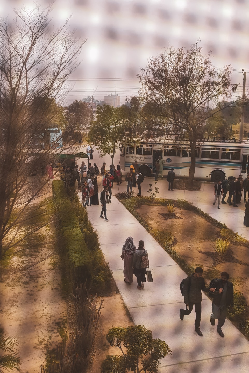 Students walk and gather around a shuttle bus on a university campus.